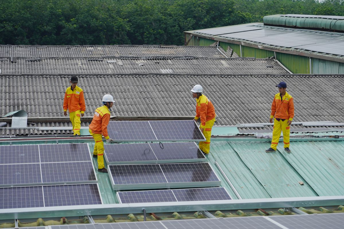 工場の屋根に太陽光パネルを設置する作業員たち