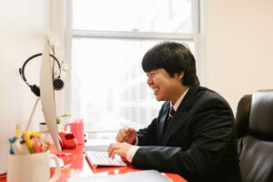 オフィスでパソコンに向かい笑顔で仕事に取り組む会社員