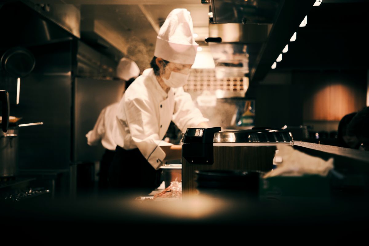 レストランの厨房で料理を仕上げる料理人
