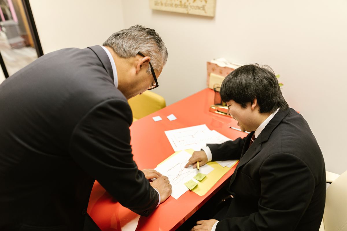 スーツ姿の社員同士が書類を見ながら相談している様子