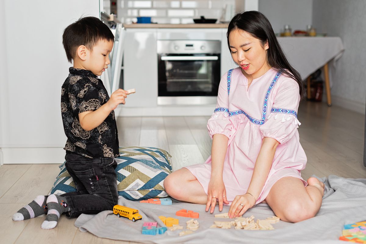 親子でカラフルなおもちゃや積み木を使って床で遊んでいる様子