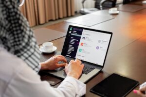 オフィスでノートPCのチャットアプリを操作するビジネスパーソン
