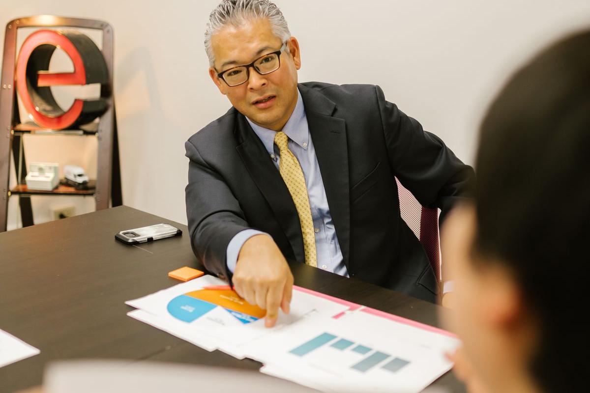 資料を指し示しながら打ち合わせを行うビジネスパーソン