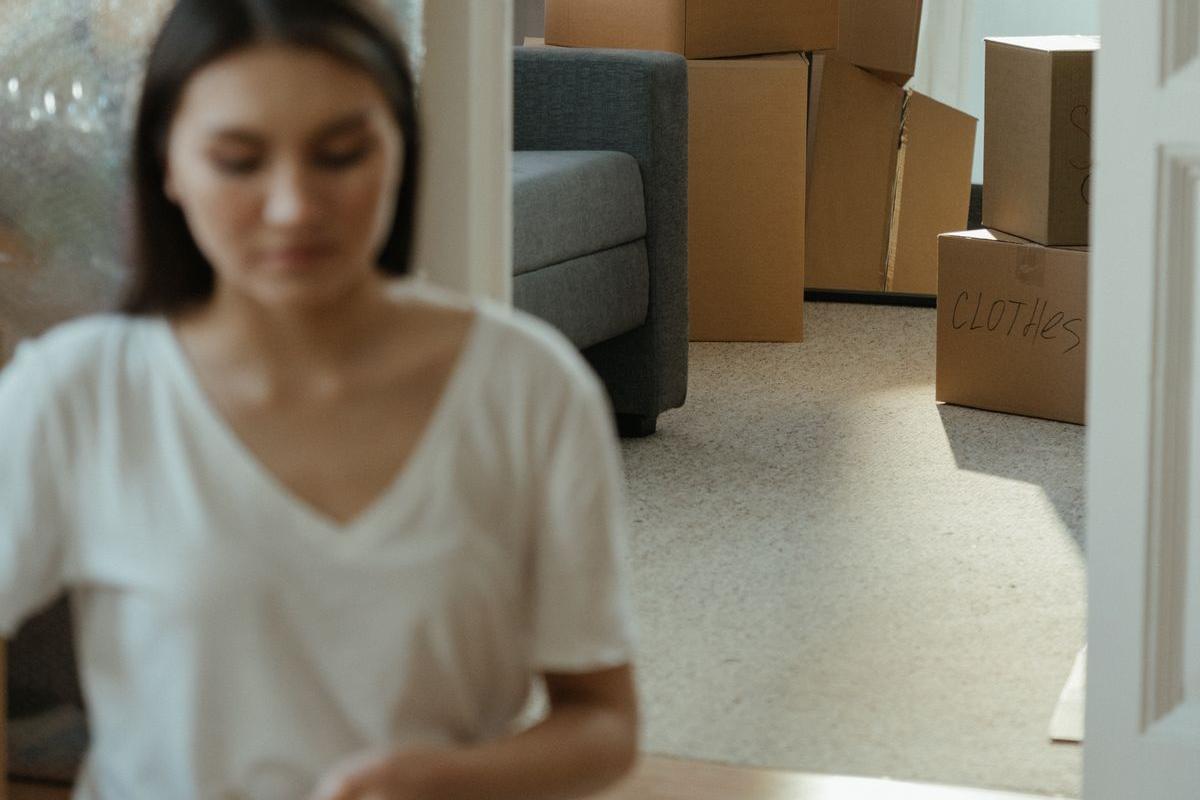 引っ越し後の部屋で荷ほどきをする人と積まれた段ボール