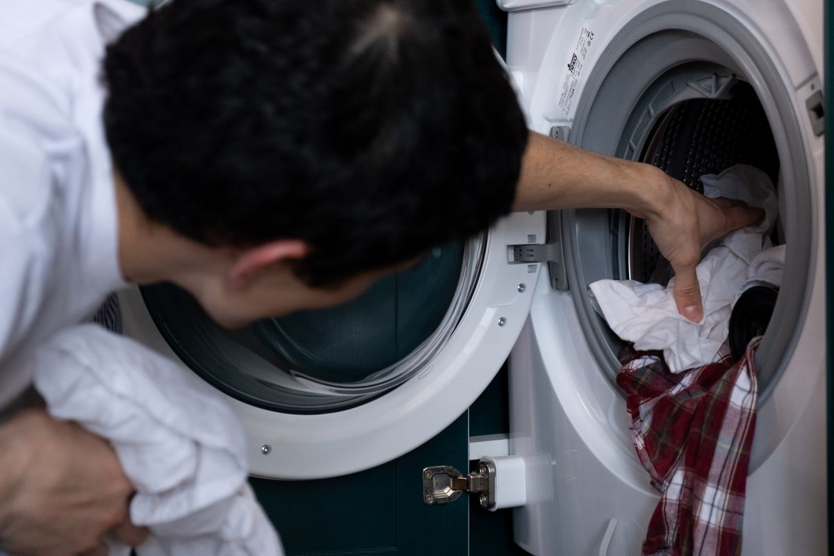 洗濯機に洗濯物を入れる人の手元