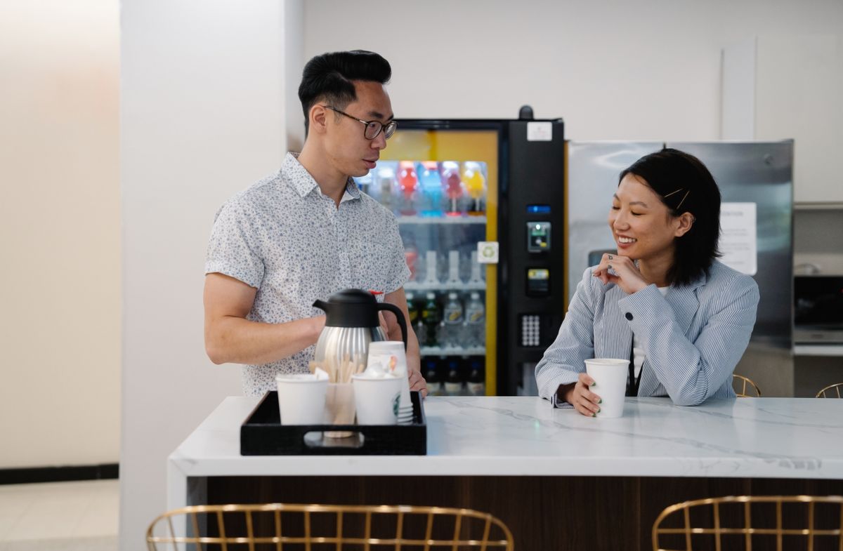 オフィスの自動販売機の前で会話する社員たち