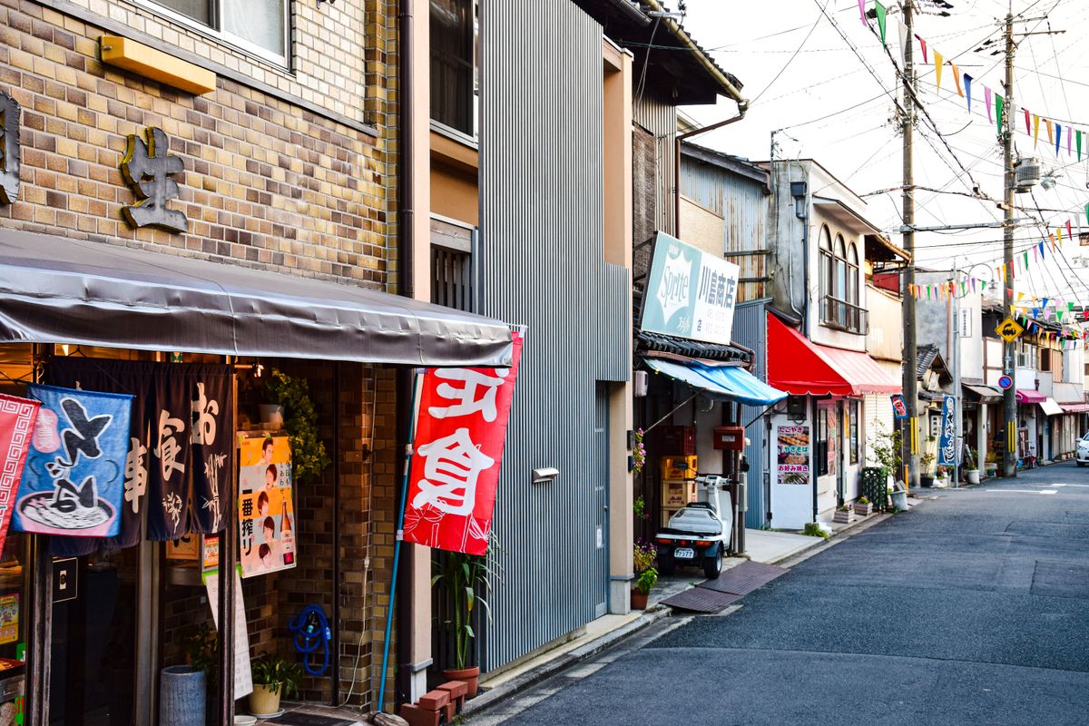 のぼりや看板が並ぶ地方の商店街の店舗前の様子