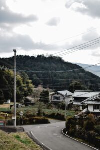 山あいの集落を通る道路と伝統的な民家、地方創生の舞台となる地域の風景