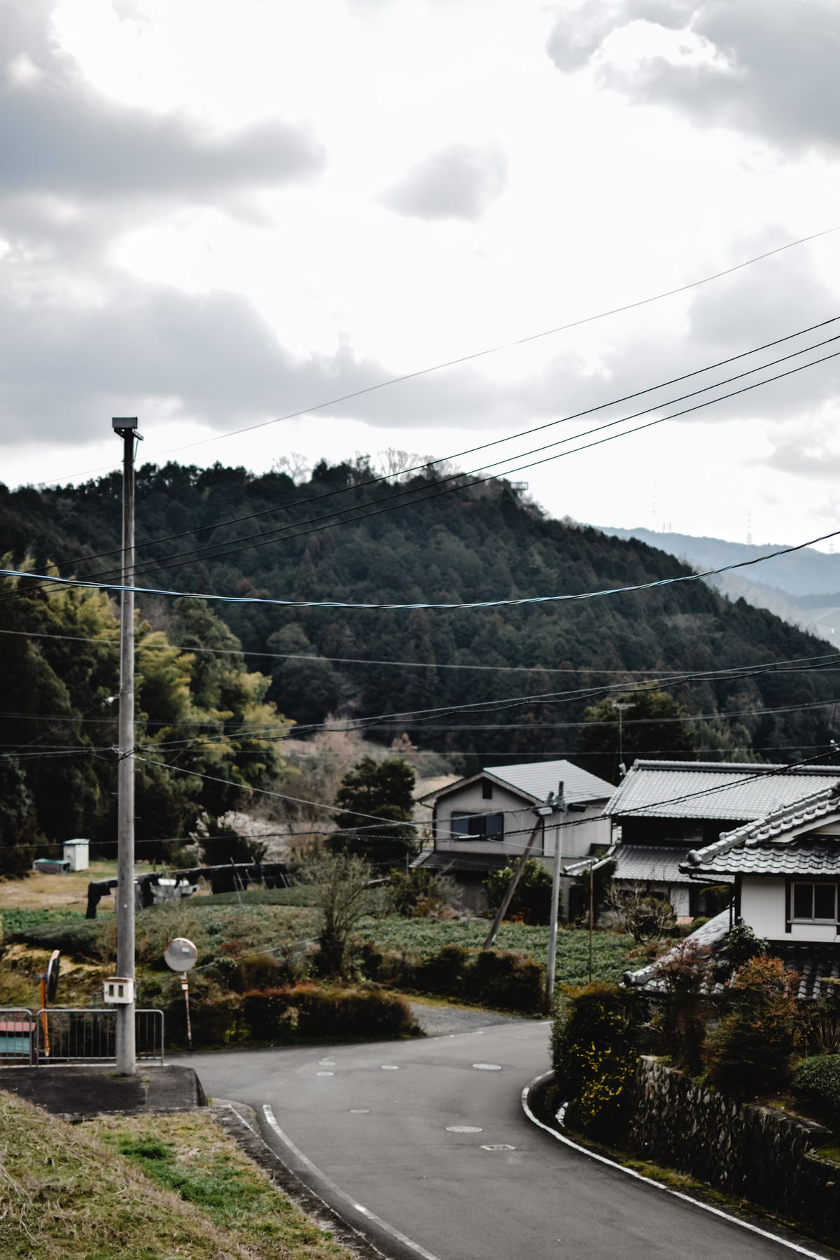 山あいの集落を通る道路と伝統的な民家、地方創生の舞台となる地域の風景