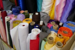さまざまな色の生地がロール状に並ぶ繊維素材の保管棚