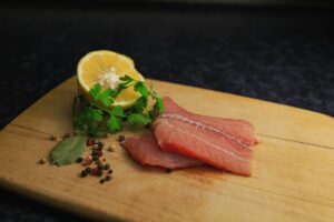 切り身の鮮魚をレモンとともに木のボードに載せた写真