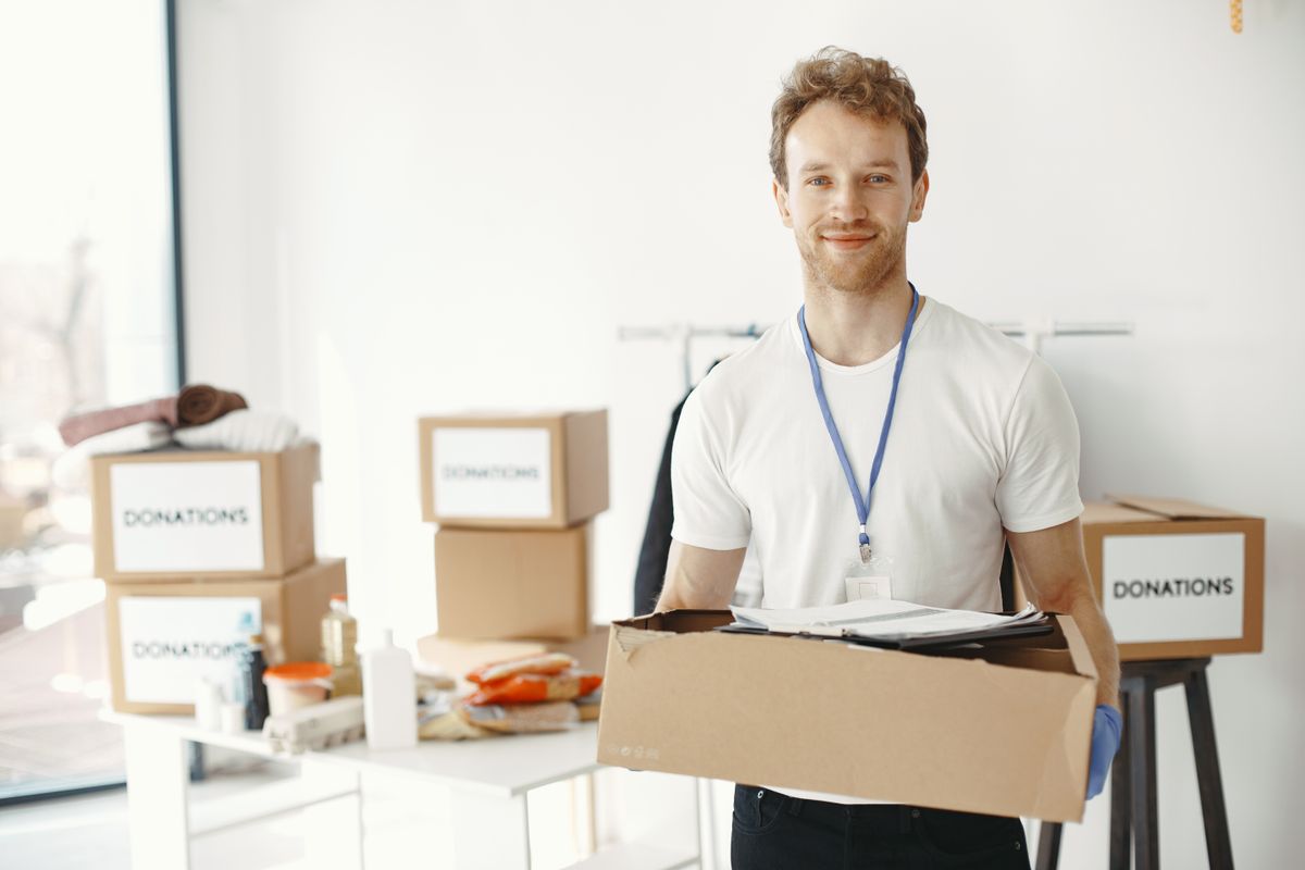 寄付用の段ボール箱を運ぶボランティアの男性