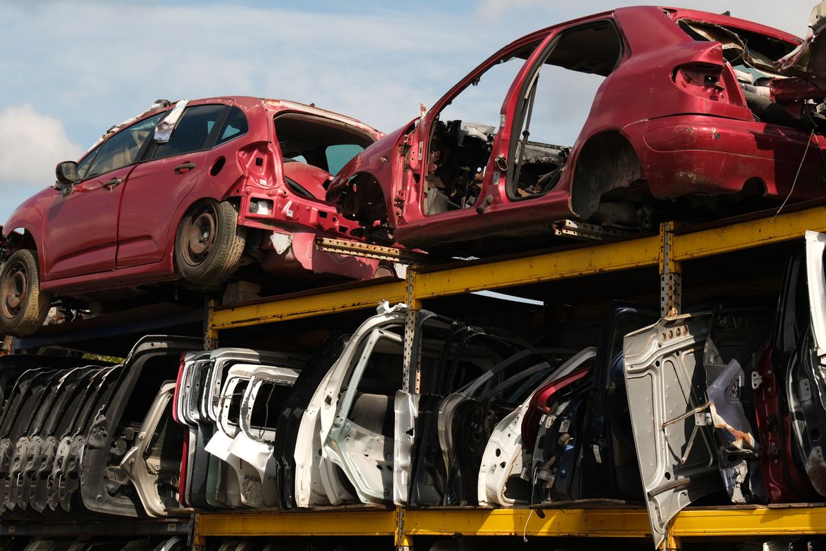 解体された廃車の車体とドアが棚に積み上げられた自動車解体場