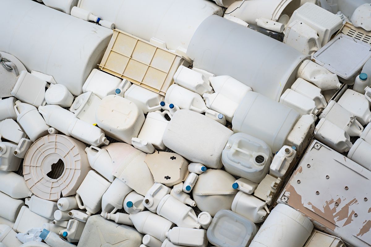 回収された白い樹脂容器やプラスチック部材が積み重なった再生原料の山