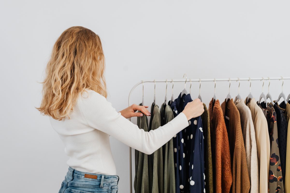 洋服サブスクのイメージとして、ラックの洋服を選ぶ女性の後ろ姿