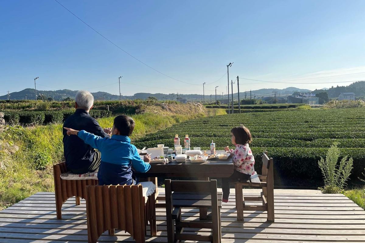 茶畑を眺めながら屋外のデッキで食事をする家族