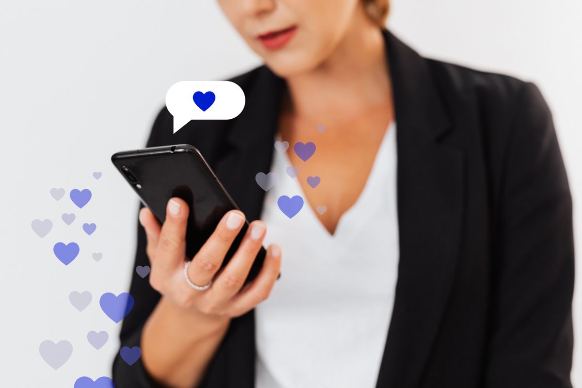 スマートフォンを持つ女性の手元にハートのアイコンが浮かぶ、オンラインで社会貢献を応援するイメージ