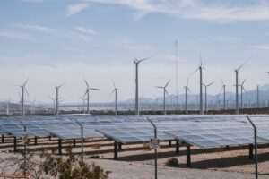 再生可能エネルギーで水素をつくるイメージとして、砂漠地帯に並ぶ風力発電の風車と太陽光パネル