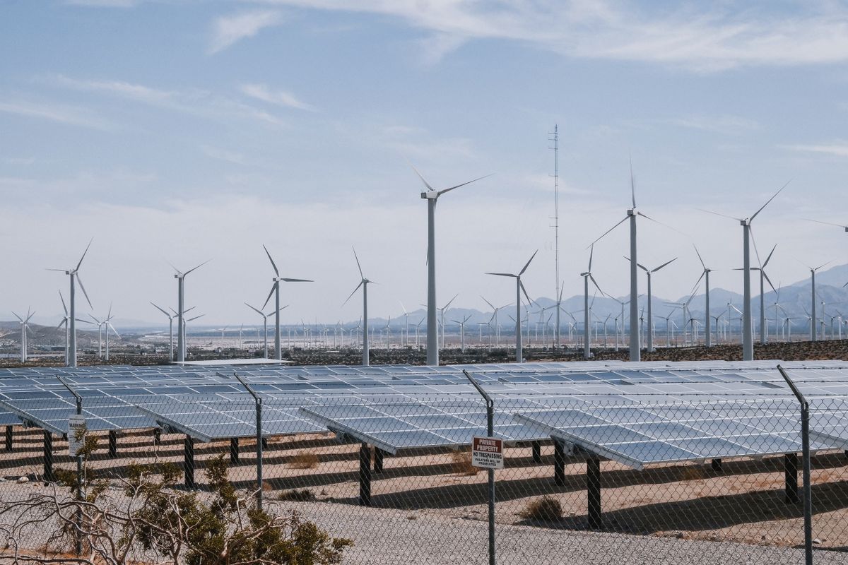 再生可能エネルギーで水素をつくるイメージとして、砂漠地帯に並ぶ風力発電の風車と太陽光パネル