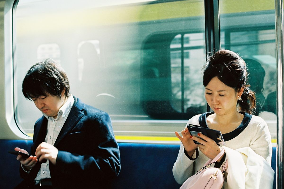 電車の中でスマートフォンを見る人たち。オンラインで社会課題の情報に触れる場面