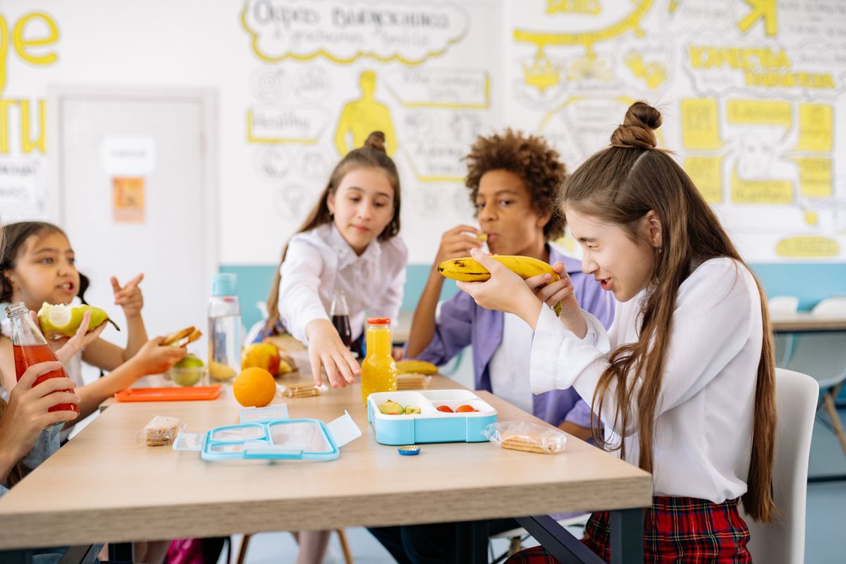 子どもたちが教室のテーブルで一緒に食事をしている様子