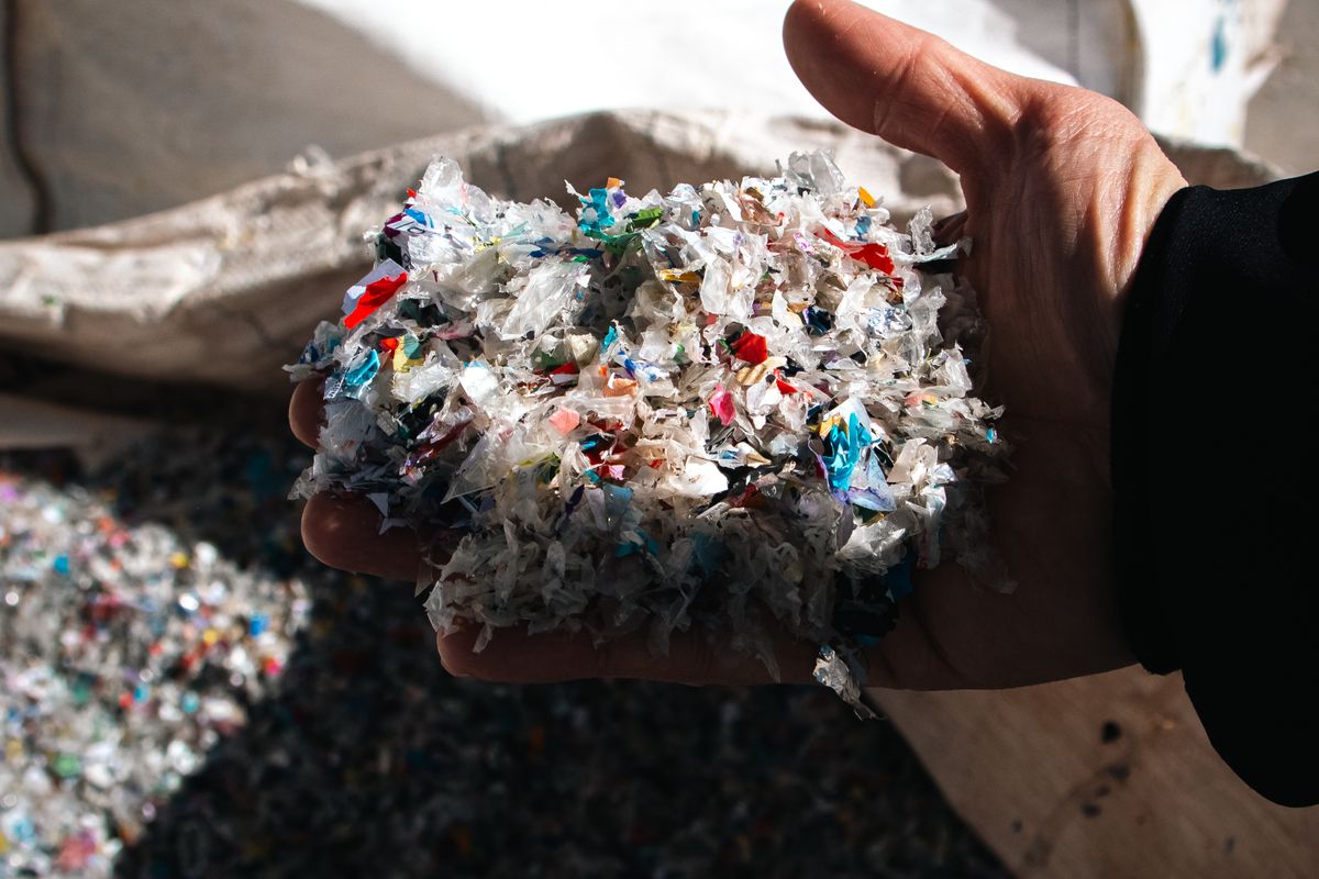 砕かれた使用済みプラスチックのフレークを手に取った様子