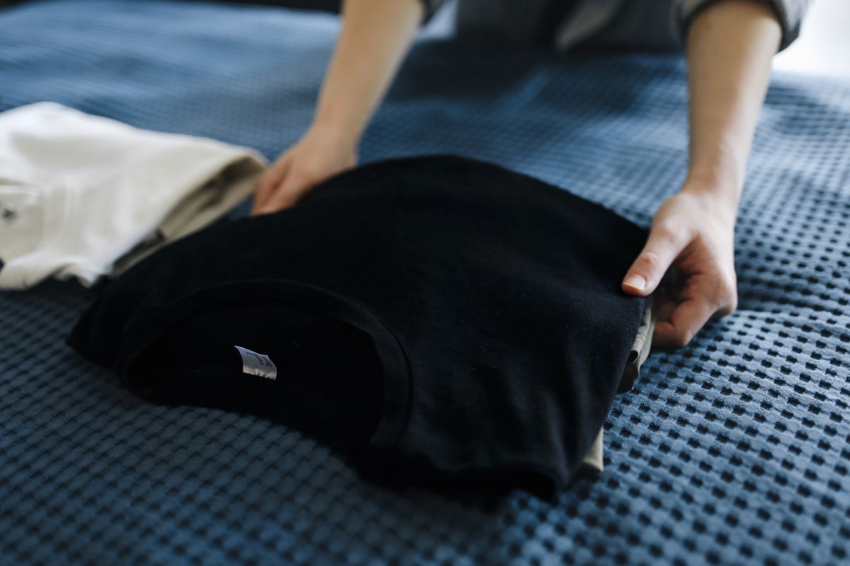 畳んだ黒いTシャツに両手を添える様子
