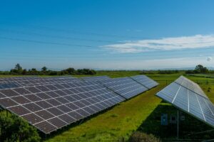 緑の草地に並ぶ太陽光パネル。再生可能エネルギーの発電所のイメージ