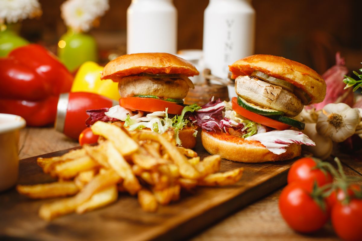 プラントベースのバーガーとポテトが木のボードに並ぶ様子