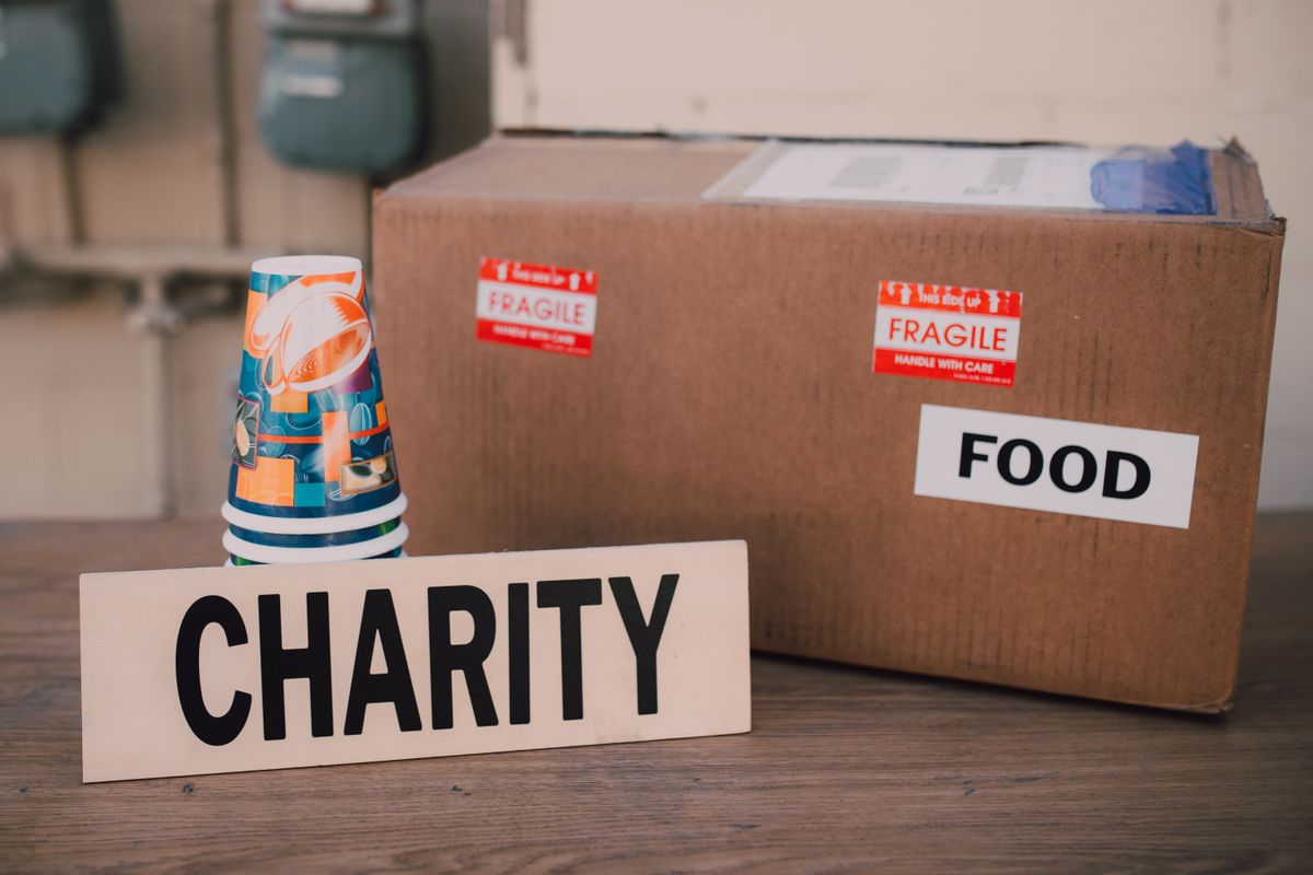 食料品の箱とCHARITYと書かれた札が置かれた寄付のイメージ