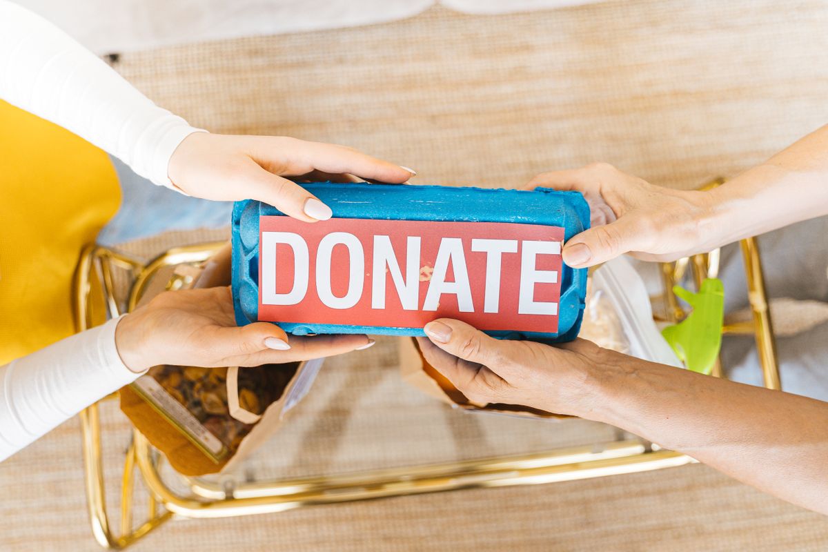楽天クラッチ募金のイメージ。DONATEと書かれた箱を受け渡す手