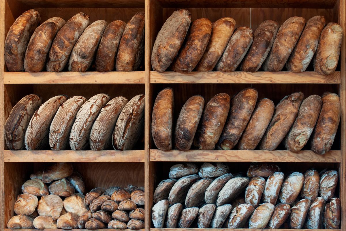 木製の棚に並ぶパン屋さんの食事パンの写真