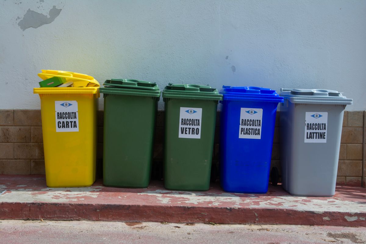 壁の前に並ぶ、紙・ガラス・プラスチック・缶用の色分けされた分別ごみ箱