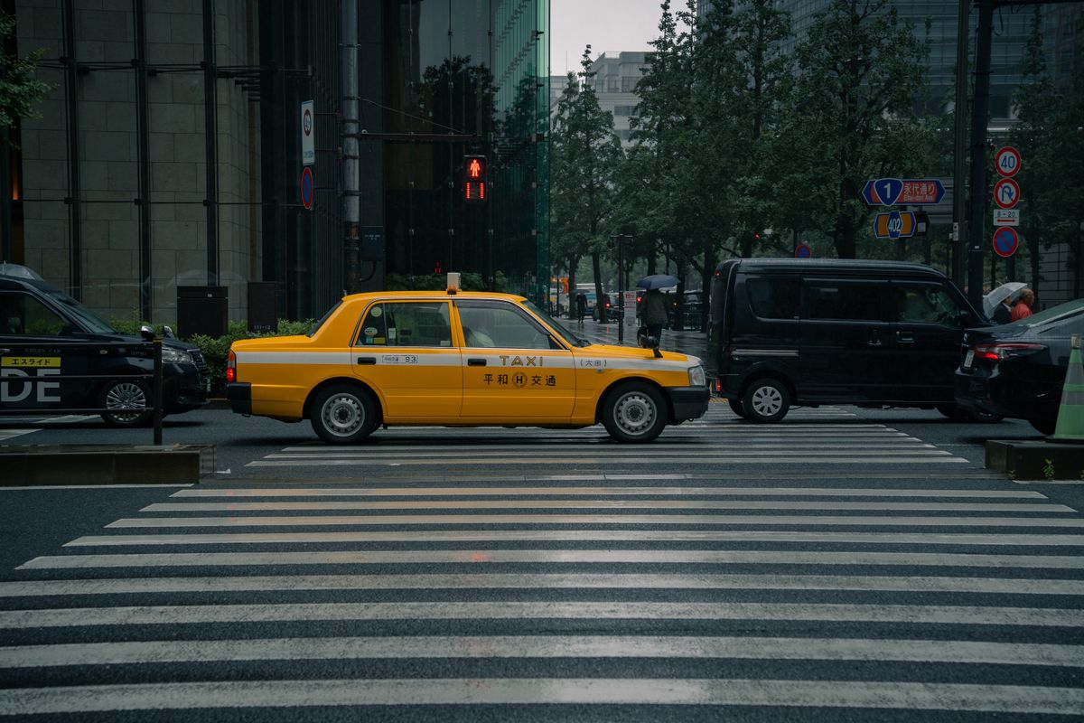 東京の交差点を走る黄色いタクシー