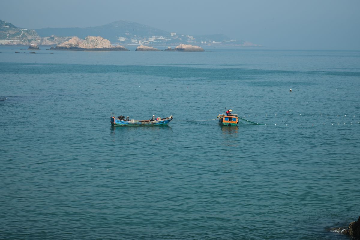 穏やかな海で網を引く漁船