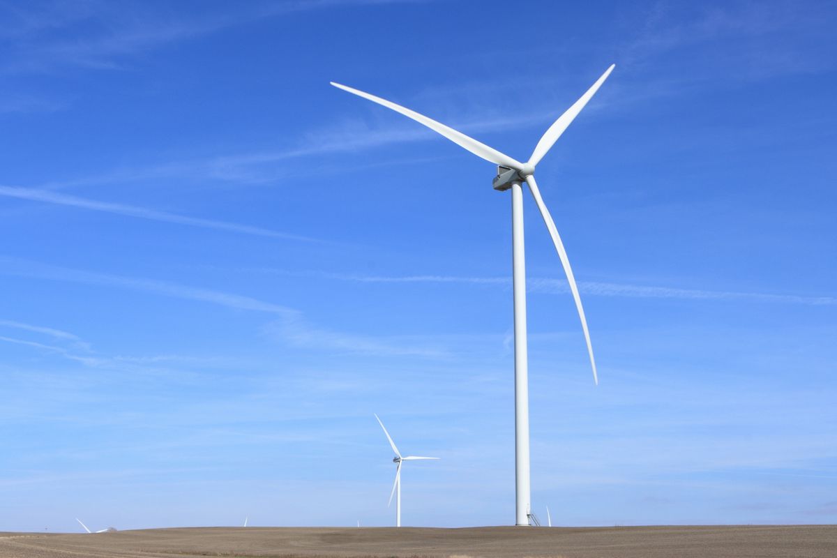 青空の下に立つ風力発電の風車