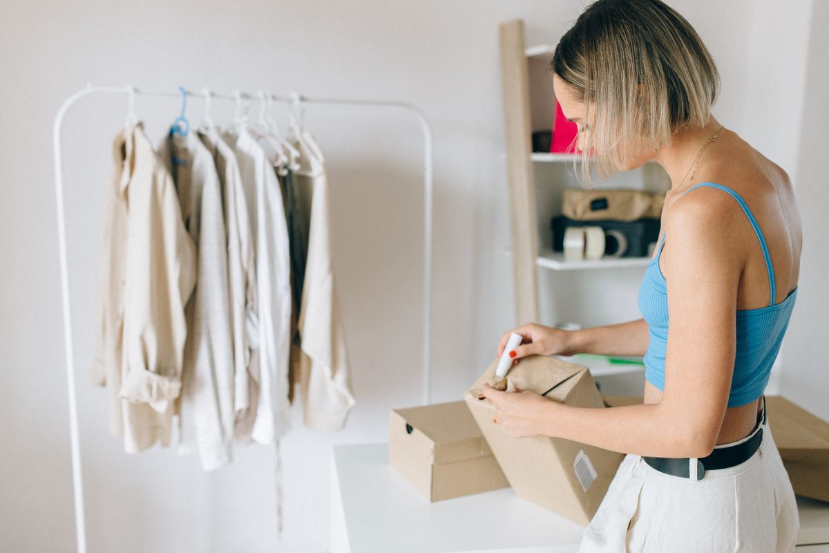 箱に服をていねいに詰める女性。返送や発送のイメージ