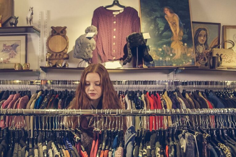 ハンガーラックの服を選ぶ女性。アウトレット通販で服を探す場面のイメージ