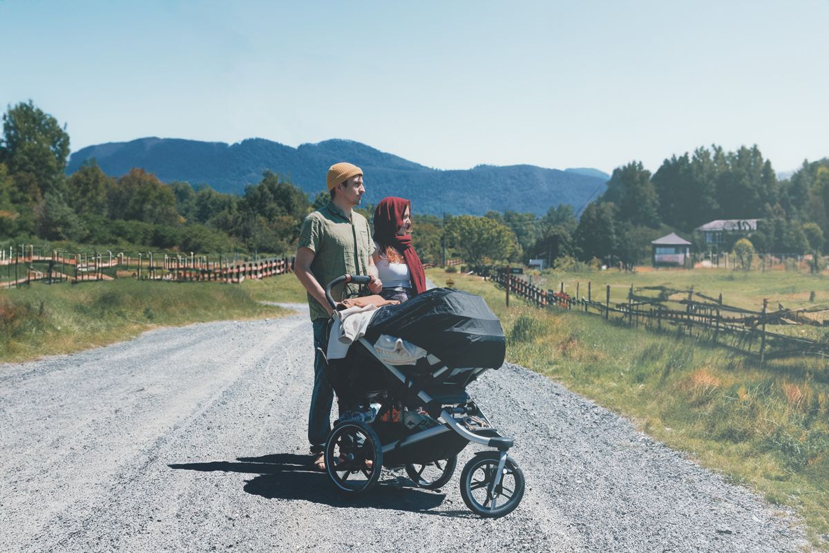 旅行先の道でベビーカーを押す夫婦