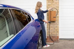自宅の壁掛け充電器で電気自動車を充電する女性